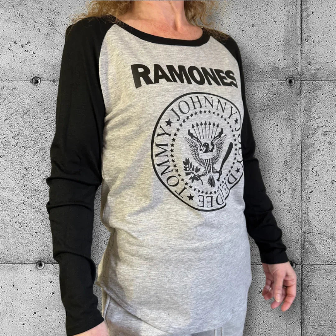 Woman wearing gray and black Ramones punk raglan tee with iconic logo on concrete background