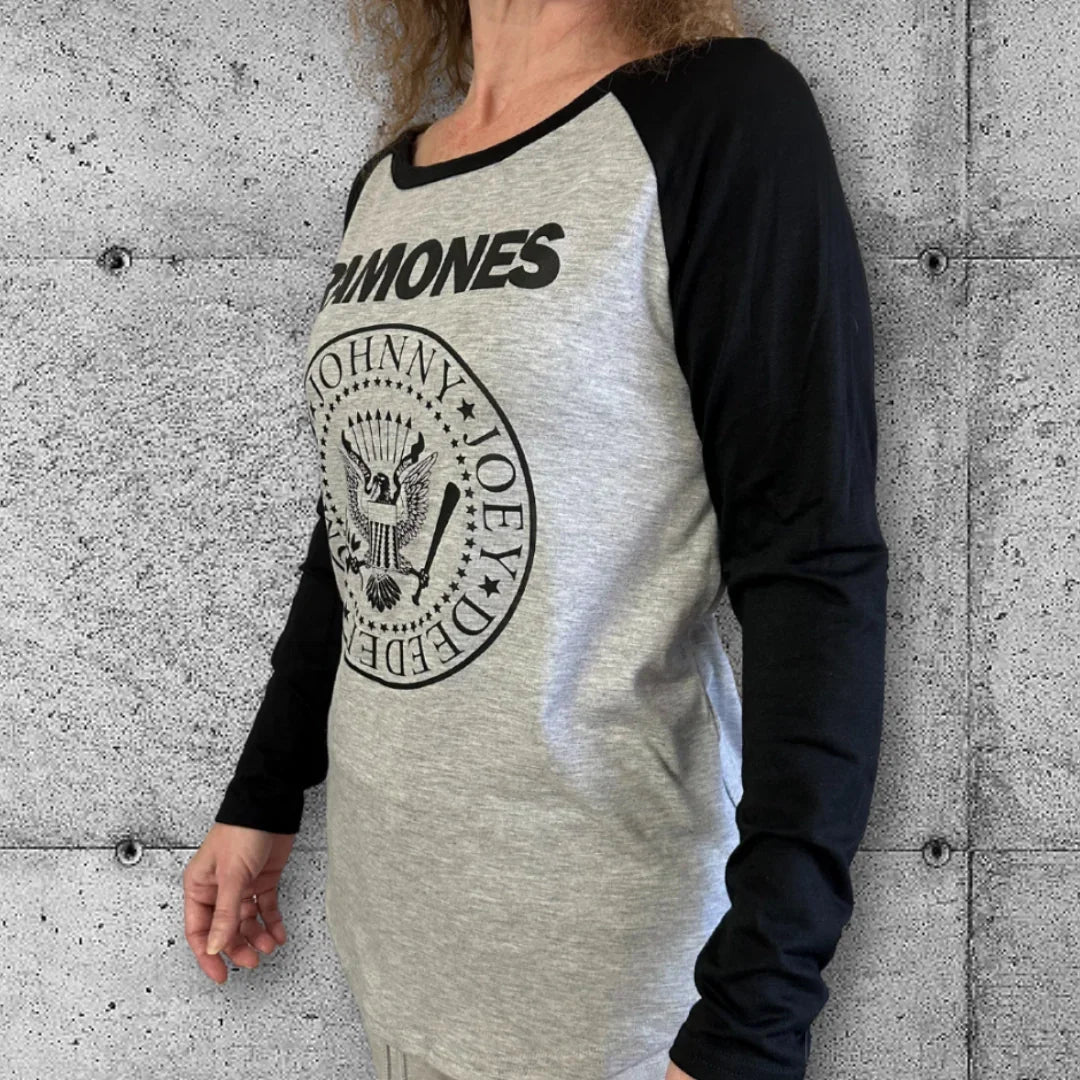 Woman wearing Ramones punk raglan tee with black sleeves, concrete wall background