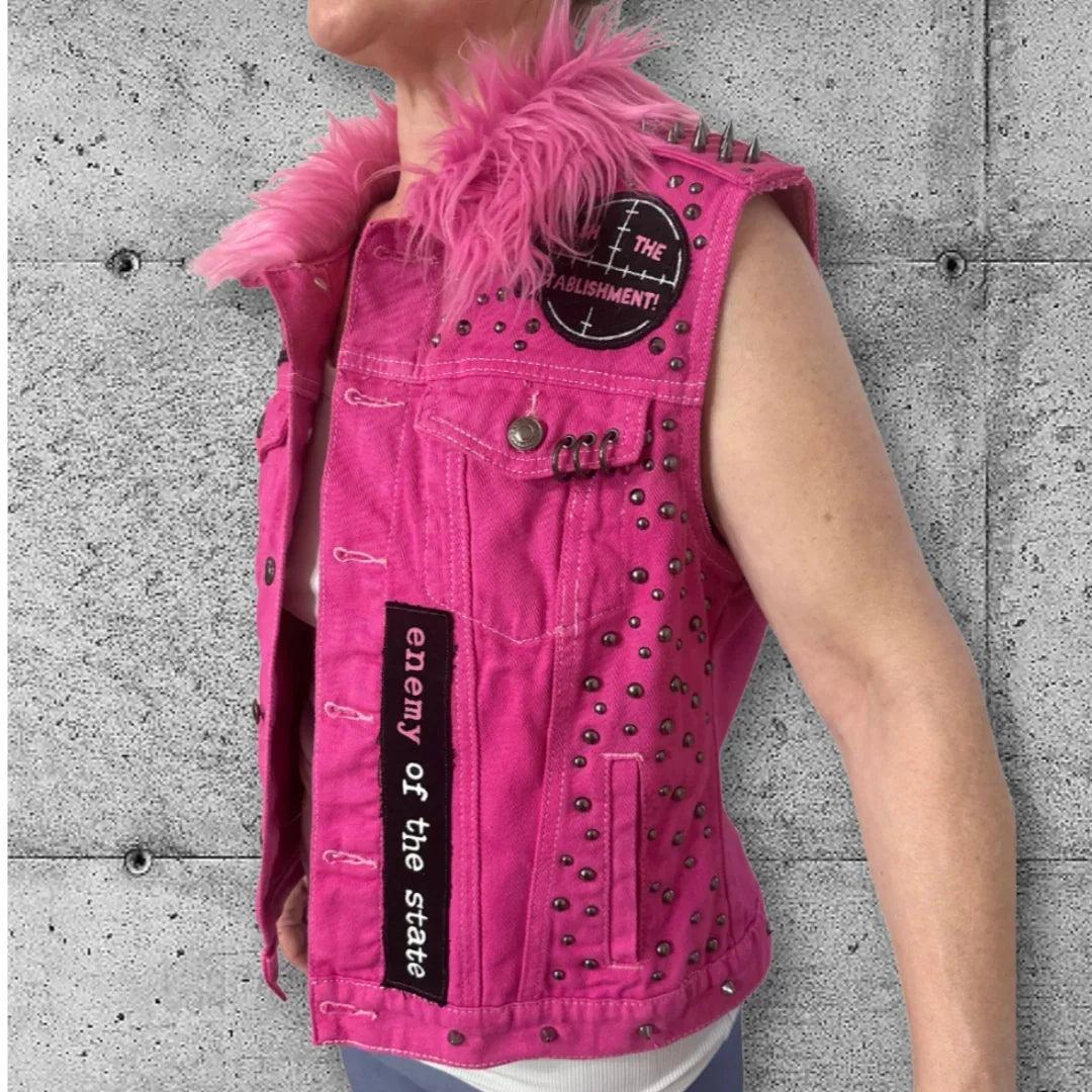 Pink studded punk vest with 'enemy of the state' patch and faux fur collar, perfect for rocker or gothic style.