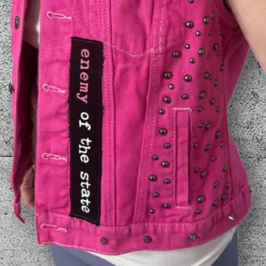 Pink punk denim vest with 'enemy of the state' patch and metal studs, edgy rocker fashion