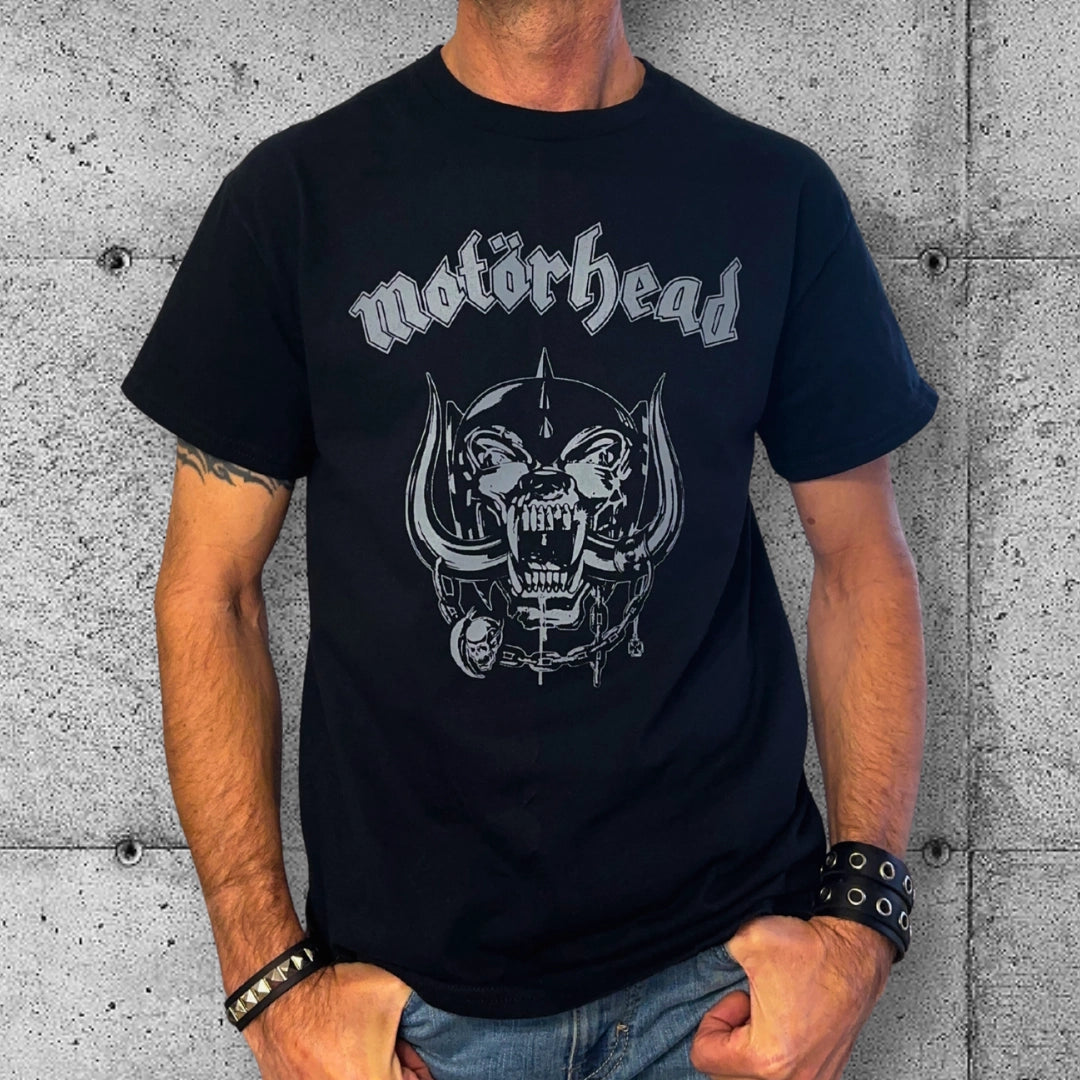 Man wearing black Motörhead logo t-shirt against concrete wall, punk rocker style clothing