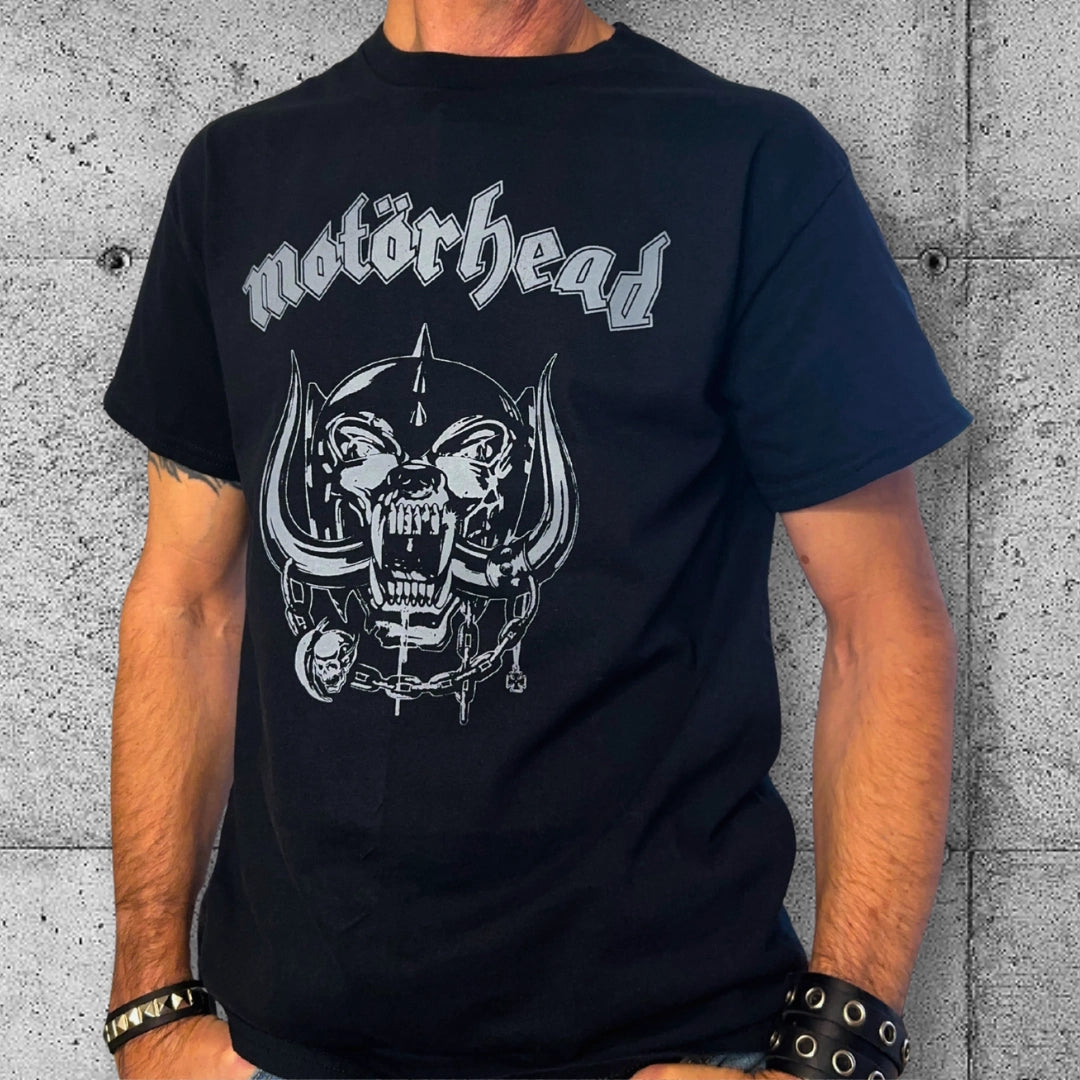 Man wearing black Motörhead logo punk rocker t-shirt against concrete wall background