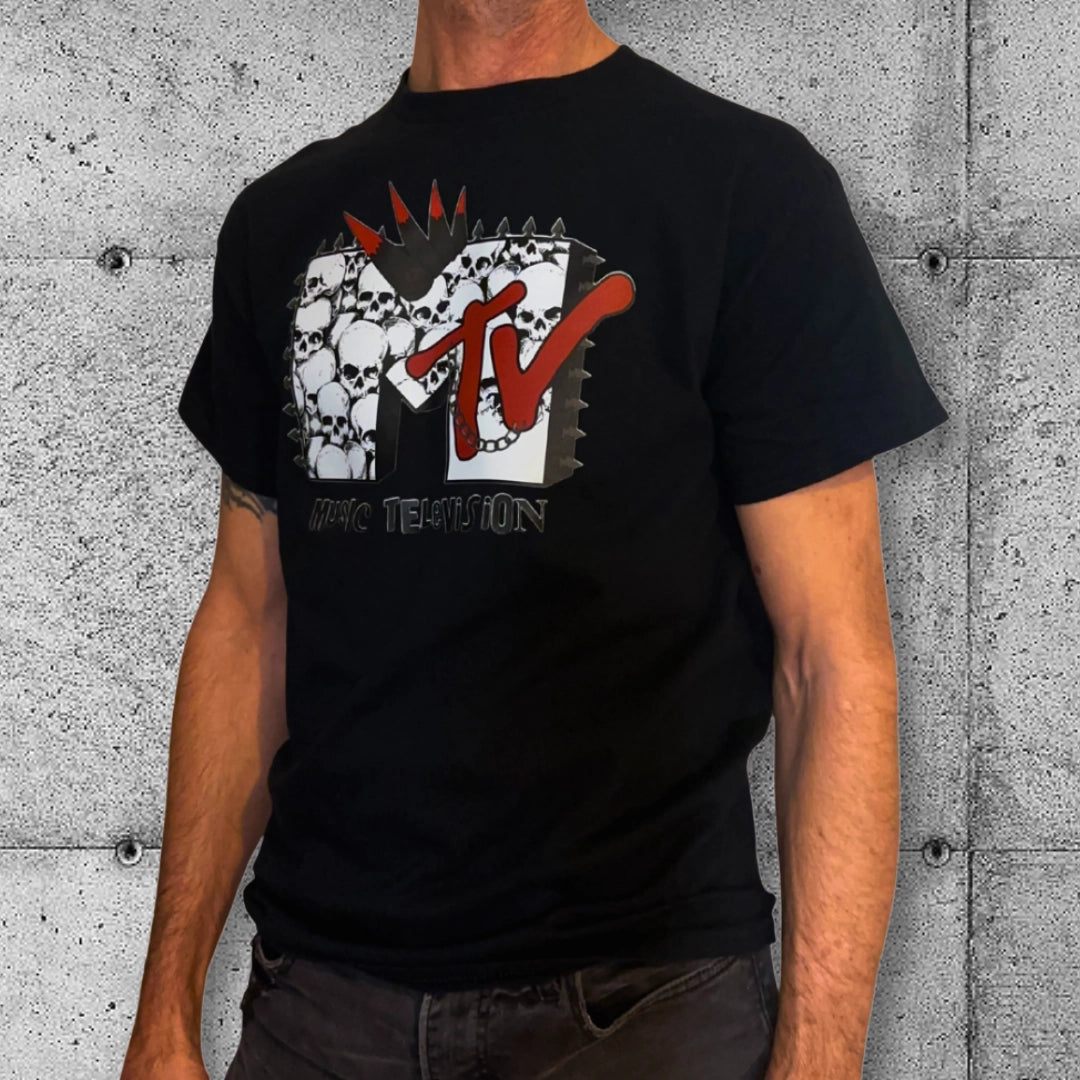 Man wearing black punk MTV T-shirt with skull graphic, rocker clothing style, concrete wall background