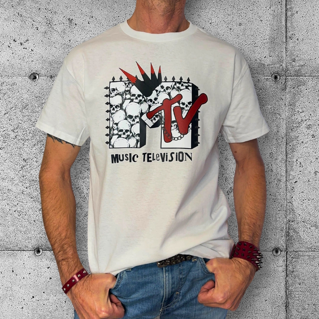 Man in punk MTV logo T-shirt with skulls, rocker style wristbands, concrete wall background