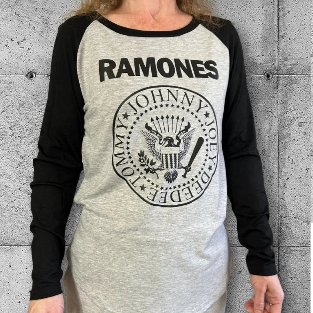 Woman wearing gray and black Ramones raglan punk band tee against concrete wall