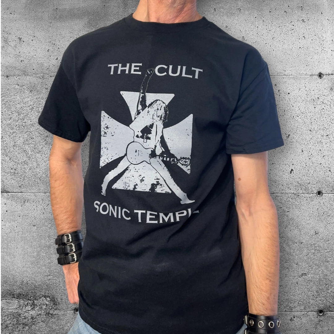 Man wearing black The Cult Sonic Temple punk rocker t-shirt with guitar graphic, concrete wall background