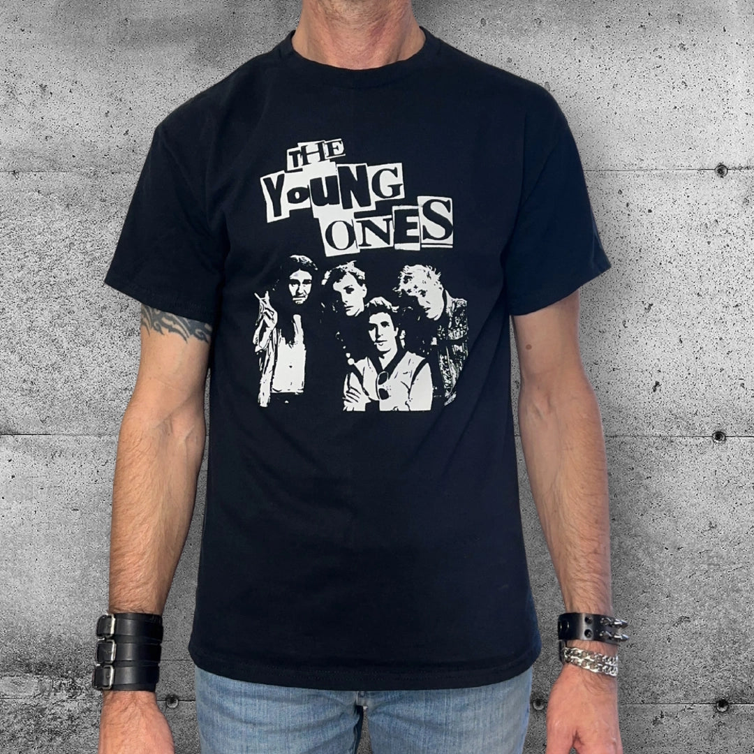 Man wearing black The Young Ones punk band t-shirt with rocker accessories, concrete wall background